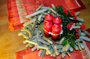 Adventskranz aus Treibholz und Tannenzweigen mit Kerzen auf einem Tisch